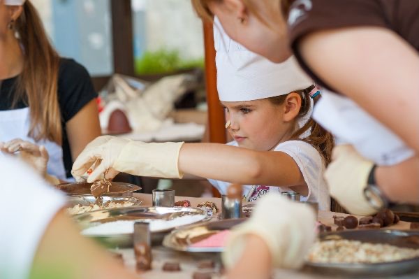 Enfants en toque de chef décorant des chocolats lors d'un atelier chocolat Anni-Zen